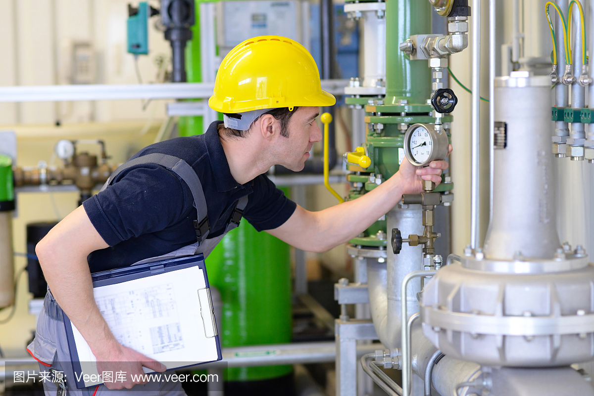 工业工人检查和修理一个有管道和技术的工厂内部的加热系统